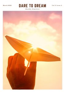 The title Dare to Dream and Monthly Newsletter below that is written in the middle on top, March 2022 on the top left corner and Vol 2 , issue 3 on the top right corner. Below is an image with a hand holding a paper rocket pointed at the sun covering the whole page.